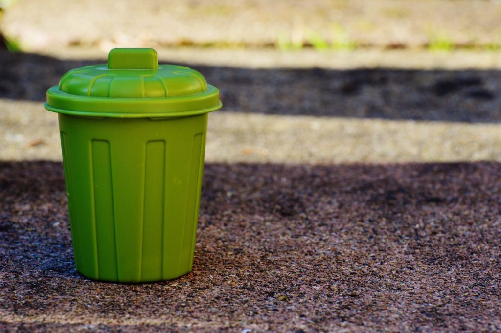 A small green garbage can with a lid.