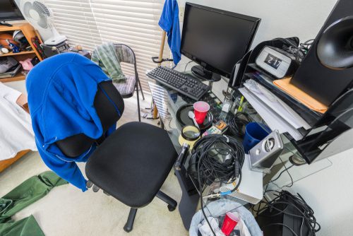 A cluttered dorm room with clothes and items everywhere.