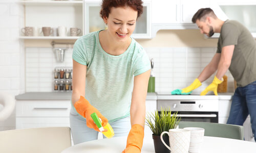A couple cleans the surfaces in their kitchen.