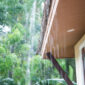 Rain drips off the edge of a home’s roof.