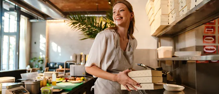 A restaurant server holds to-go boxes in the kitchen. Food service companies are some of the most common places for pests, but thankfully Gregory Pest Solutions can help you keep them away.