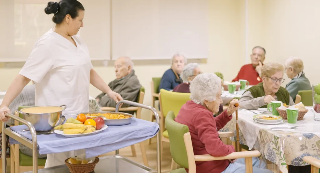 cook serving food to care home residents in dining room