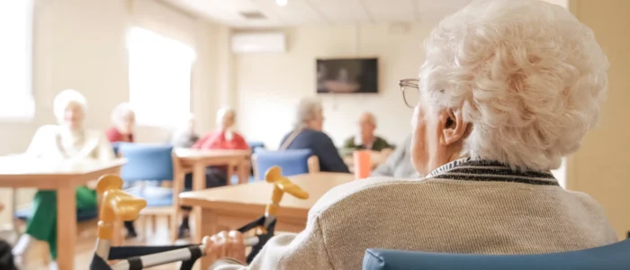 Elderly woman in chair sitting with her waker in dining room of care home